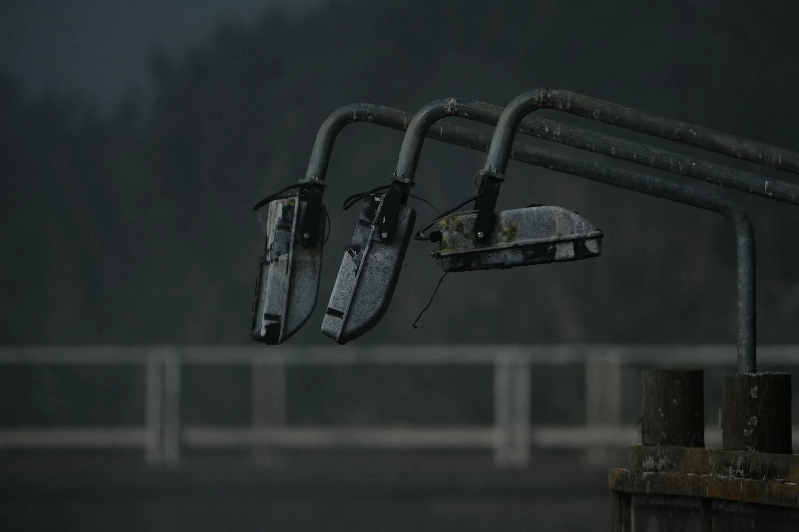 Weathered floodlights above a rail on a grey morning